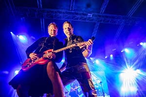 Gitarrist und Sänger nebeneinander im blauem Bühnenlicht auf einem Stadtfest