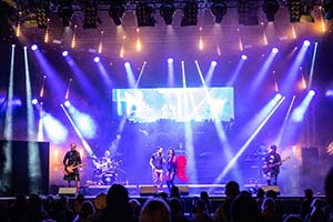 Blick von vorne auf die Bühne mit der Band im wies/blauem Bühnenlicht auf einer Firmenfeier